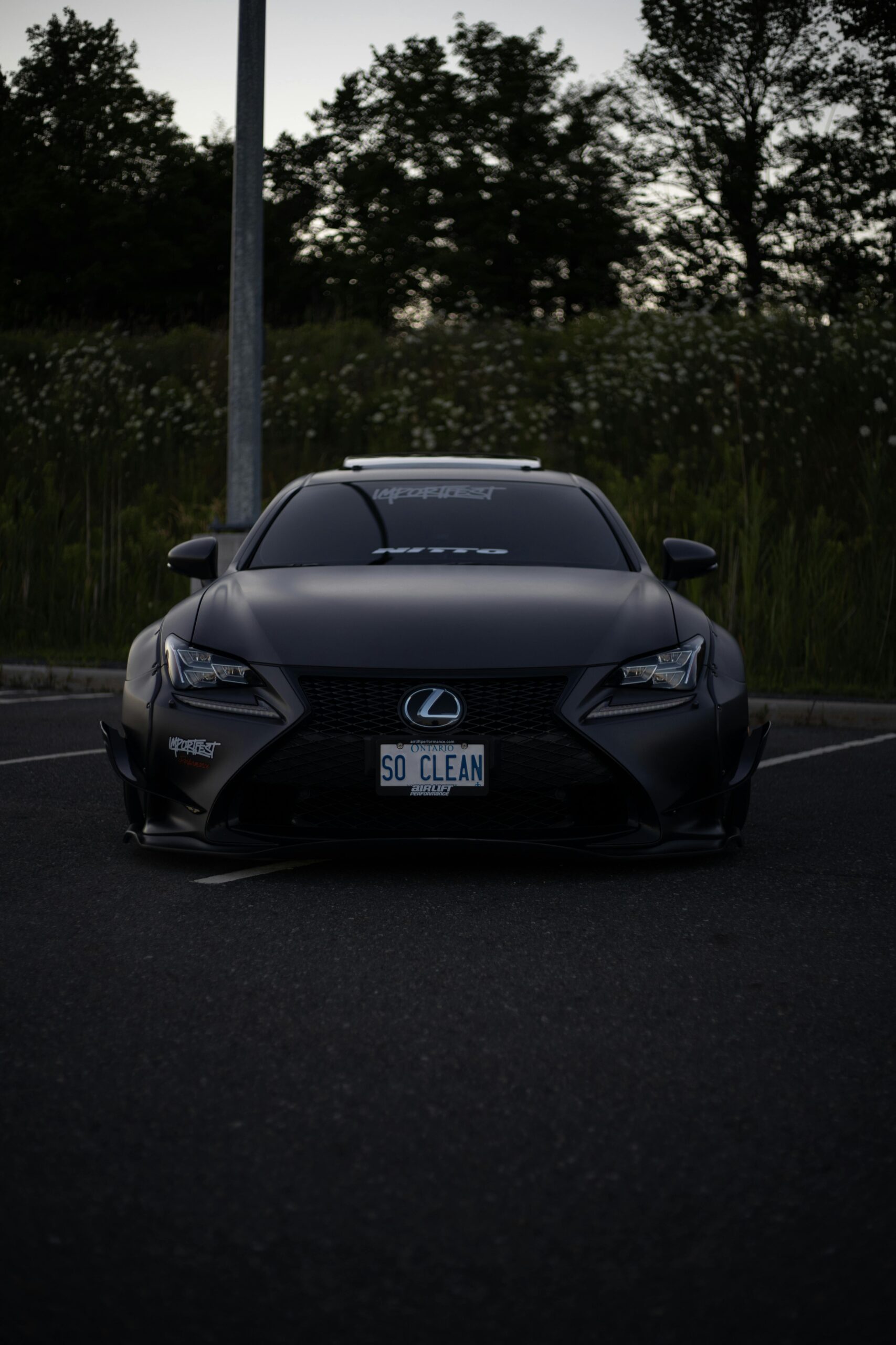 Front view of a luxury Lexus car parked outdoors at dusk with a custom license plate.
